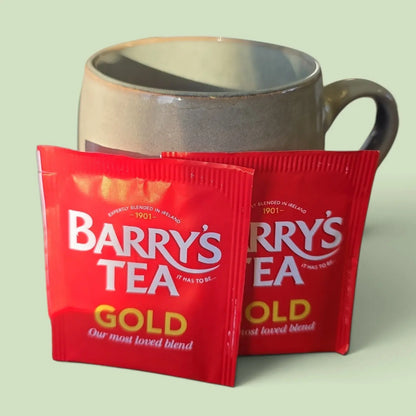Two Barry's Tea Gold teabags in front of a grey mug