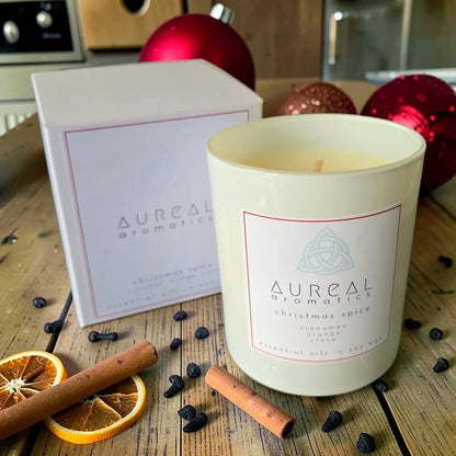 Aureal Christmas Spice candle in a white glass with its box, cinnamon and orange slices