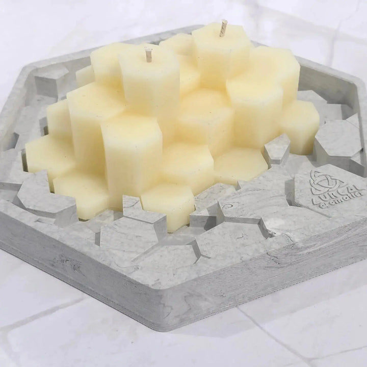 Cream beeswax Giant's Causeway candle of hexagon columns sitting in a grey hexagon base