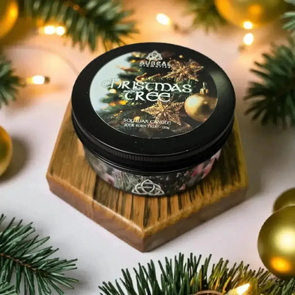 Christmas Tree soy wax candle tin on a wooden stand among pine and gold baubles