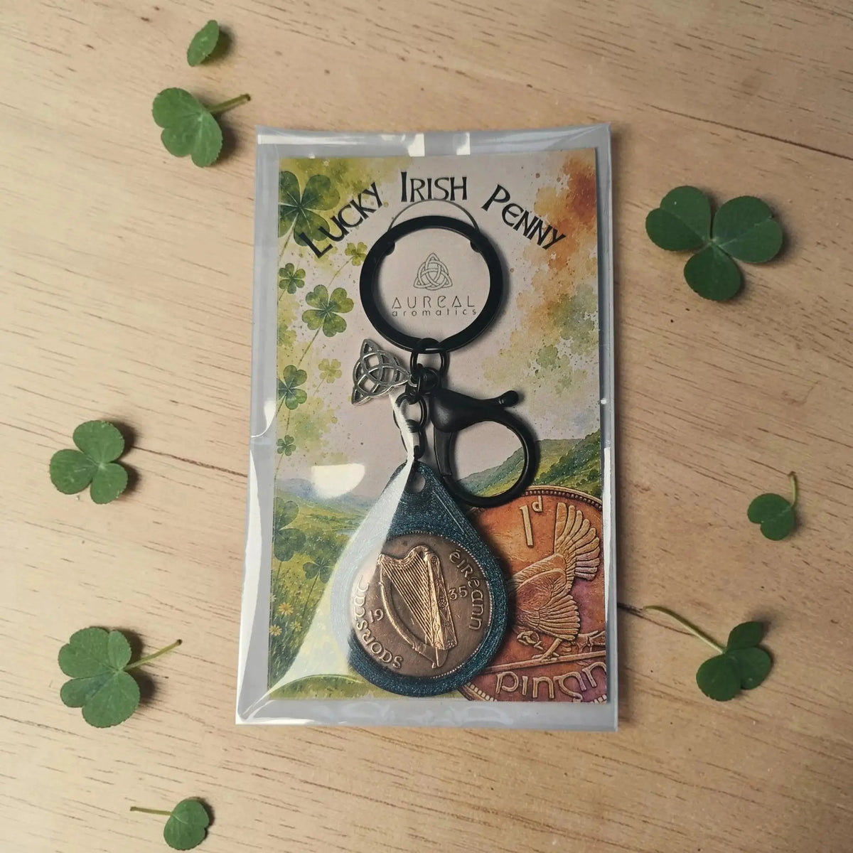 Lucky Irish Penny keyring in its packet, with shamrock leaves on wood