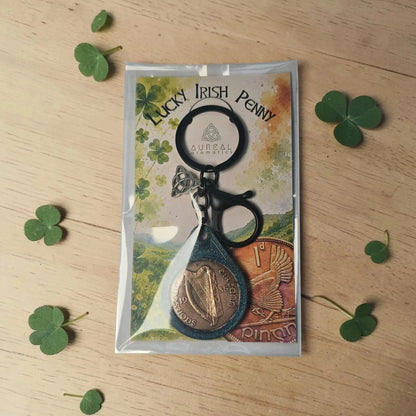 Lucky Irish Penny keyring in its packet, with shamrock leaves on wood