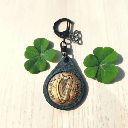 Irish penny keyring showing the harp side dated 1935, between two four-leaf clovers