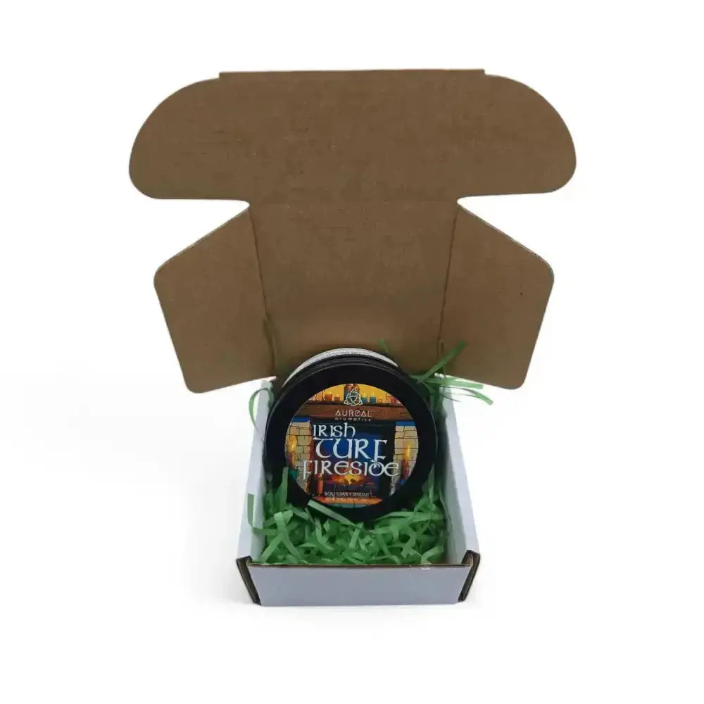 Irish Turf Fireside candle tin in an open brown mailer box with green paper shred