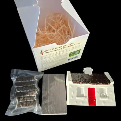 Opened cottage set box with a sealed pack of turf sods, a slate and the white cottage burner