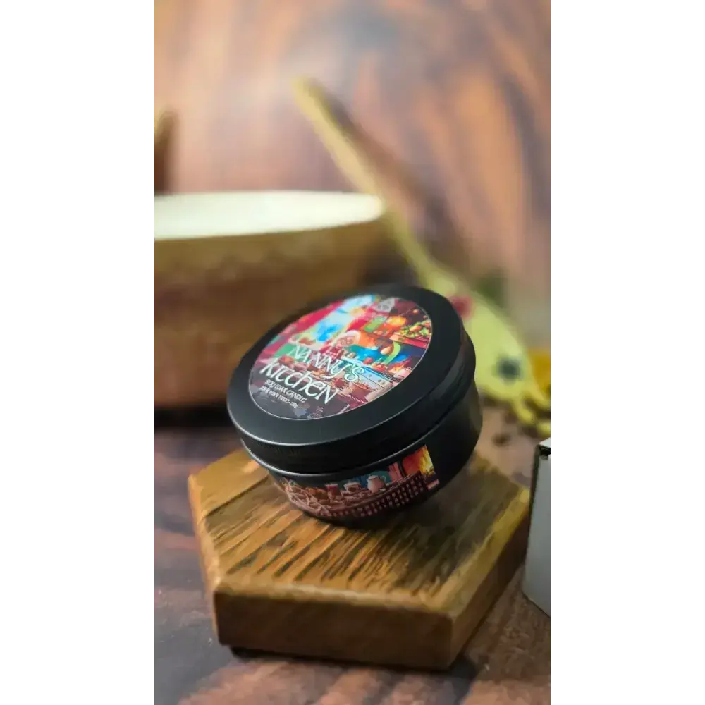 Nanny's Kitchen candle tin on a hexagon wooden stand, a mixing bowl behind