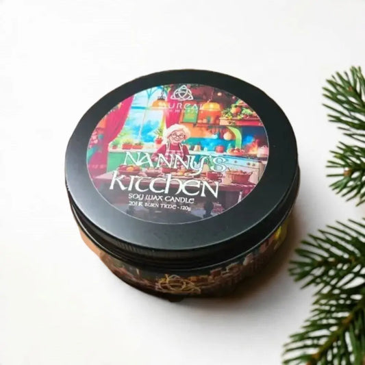 Nanny's Kitchen soy wax candle tin beside a pine branch