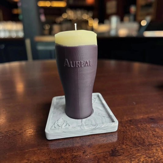 Pint of stout candle on a square marble effect base on a wooden pub table