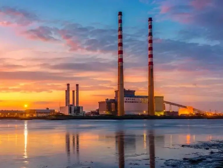 The red and white Poolbeg chimneys by the water at sunset